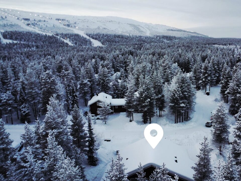 Aerial view of the snowy forest around Chalet Nulkka with the Levi slopes behind