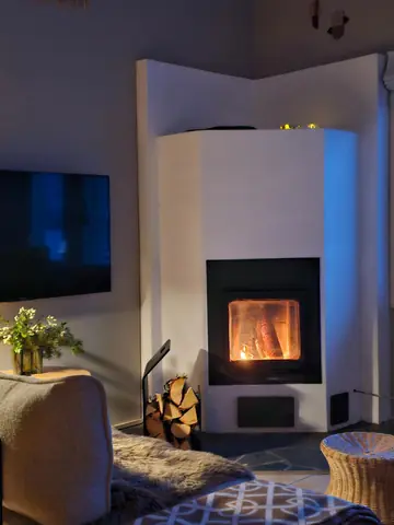 The stone fireplace of Chalet Nulkka lit on a winter evening