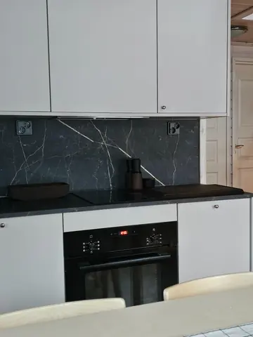 White kitchen cabinets and dark stone splashback at Chalet Nulkka