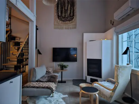Bright living room of Chalet Nulkka in daylight with sofa, armchair and fireplace