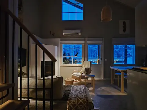 Evening in the living room of Chalet Nulkka with the fireplace lit and blue winter light in the windows