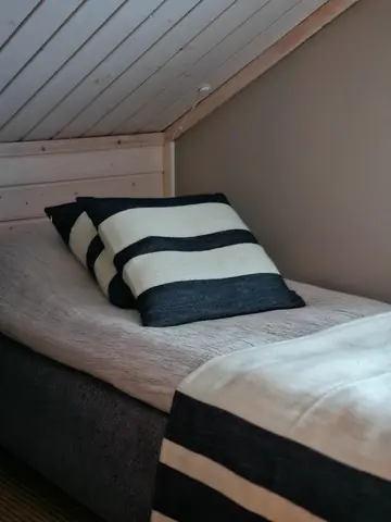 Single bed with striped cushions and wool throw upstairs